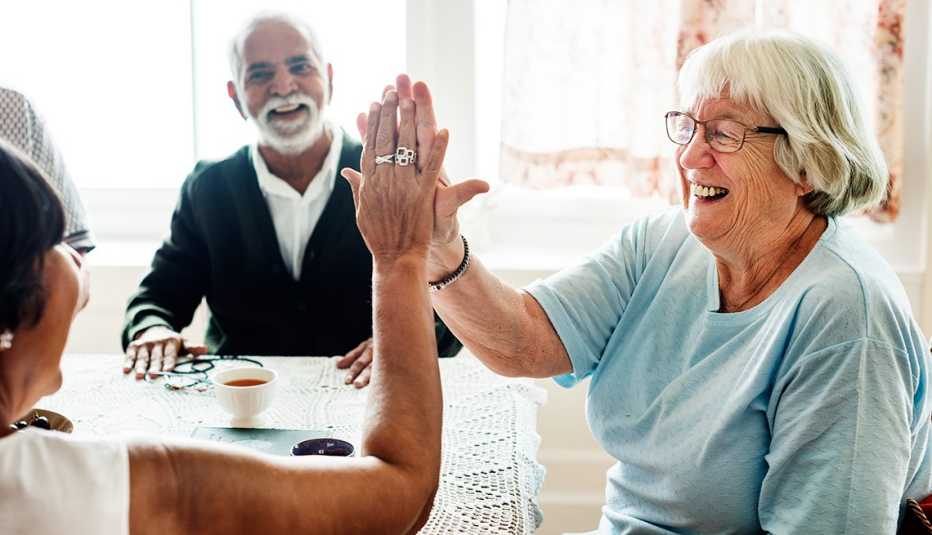 Dos mujeres mayores sonríen mientras se chocan las manos.