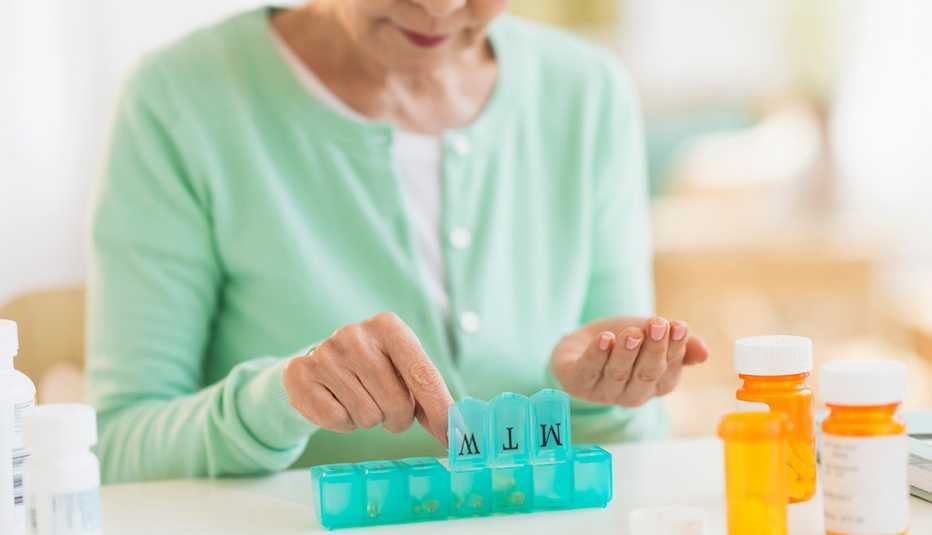Mujer organiza pastillas de medicamentos recetados