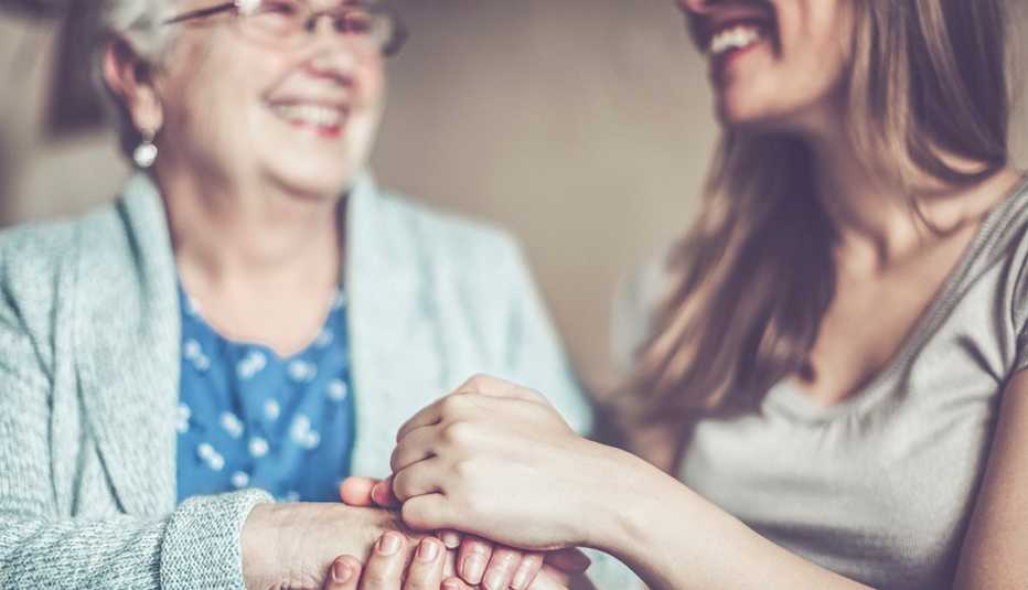 Mujer sostiene las manos de su madre mientras sonríen