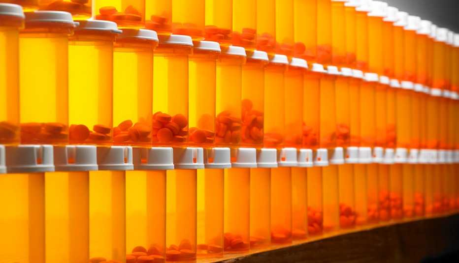 Frascos con pastillas de color naranja apilados en una pared
