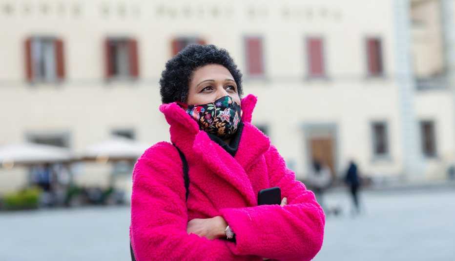 Una mujer en una plaza con su abrigo y mascarilla puesta