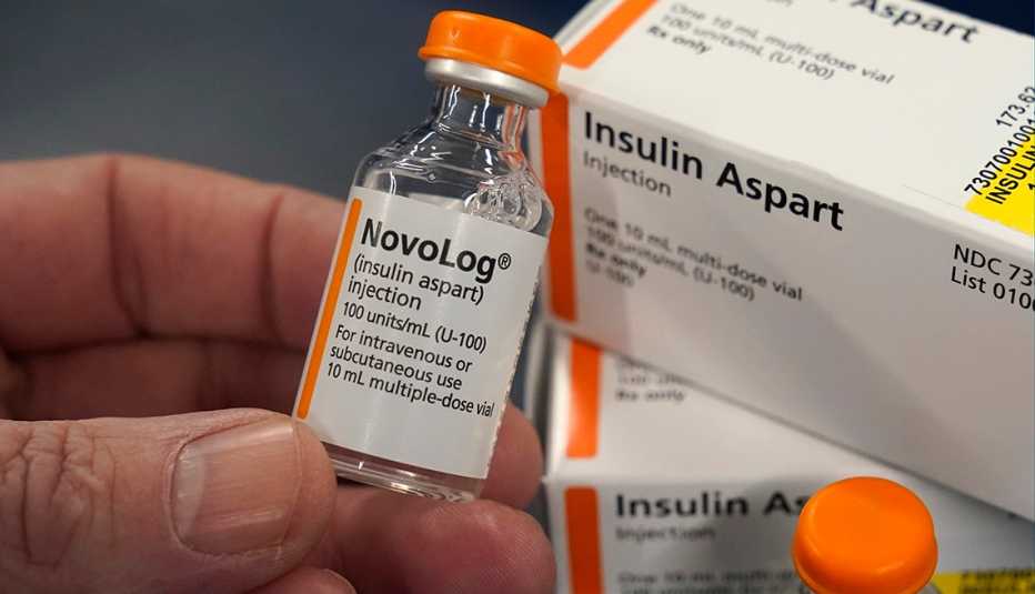 Una persona sostiene un frasco de insulina y de fondo dos cajas de insulina