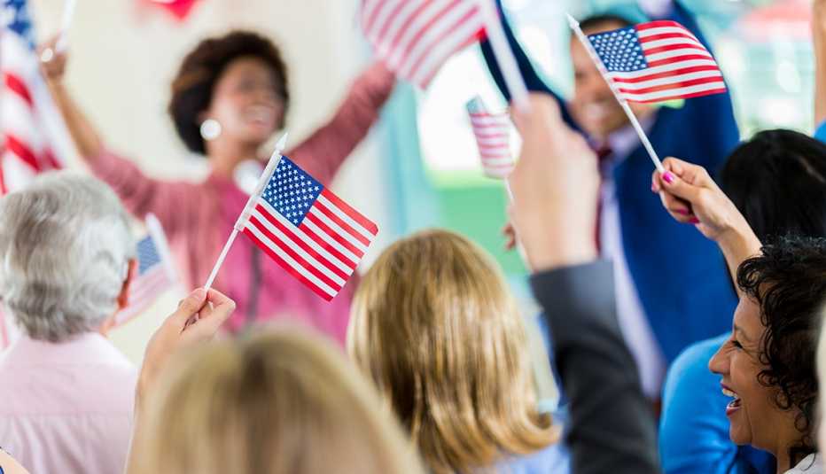Personas agitan banderas de Estados Unidos con la mano