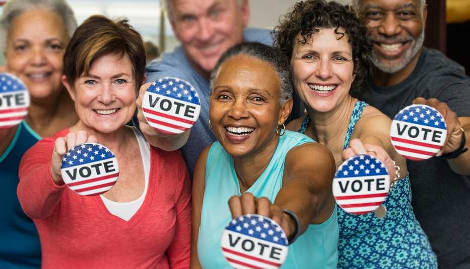 Votantes mayores sostienen en la mano botones que dicen -Vote-