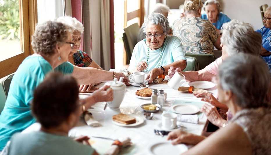 Grupo de mujeres mayores sentadas alrededor de una mesa desayunando