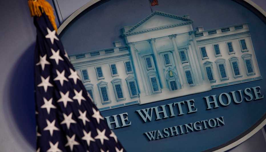 Imagen de la Casa Blanca junto a una bandera de Estados Unidos