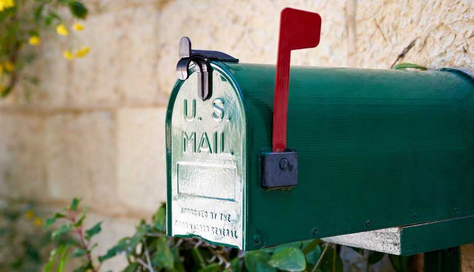 Buzón de correo verde frente a un muro