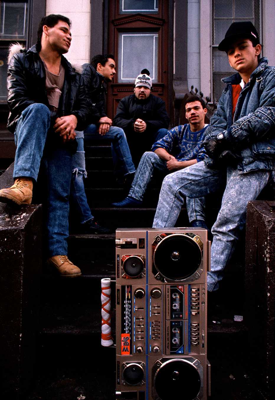 Grupo de jóvenes sentados en un portal con una grabadora de casete