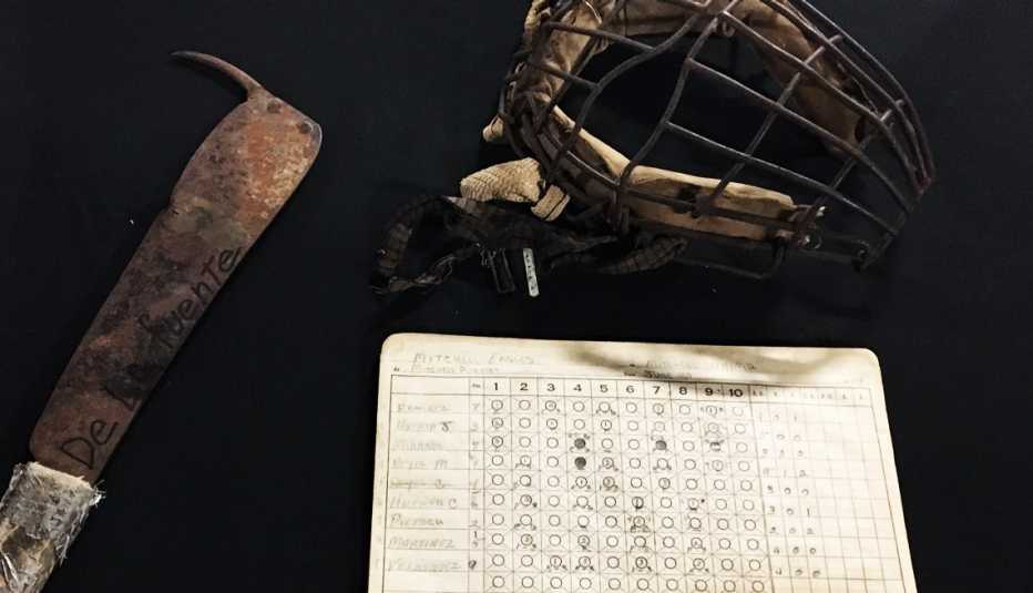 Careta de béisbol y una libreta de anotaciones junto a una herramienta de labranza.