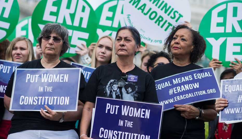 Grupo de mujeres sostienen carteles que dicen en inglés -E R A Yes- y -Put Women in the Constitution-