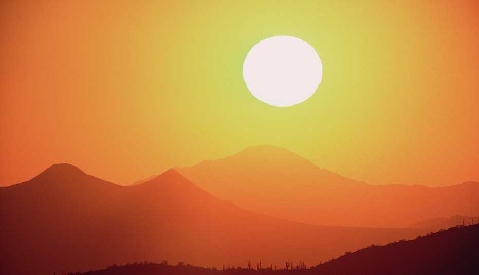 El sol en el horizonte sobre las montañas