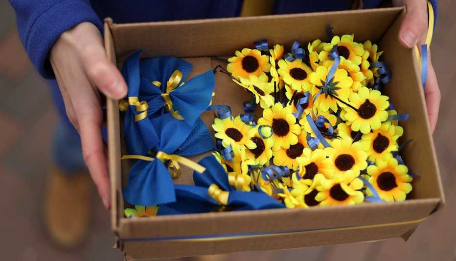 Manos de una persona sostienen una caja con girasoles y cintas azules que representan el apoyo a Ucrania. Washington, DC