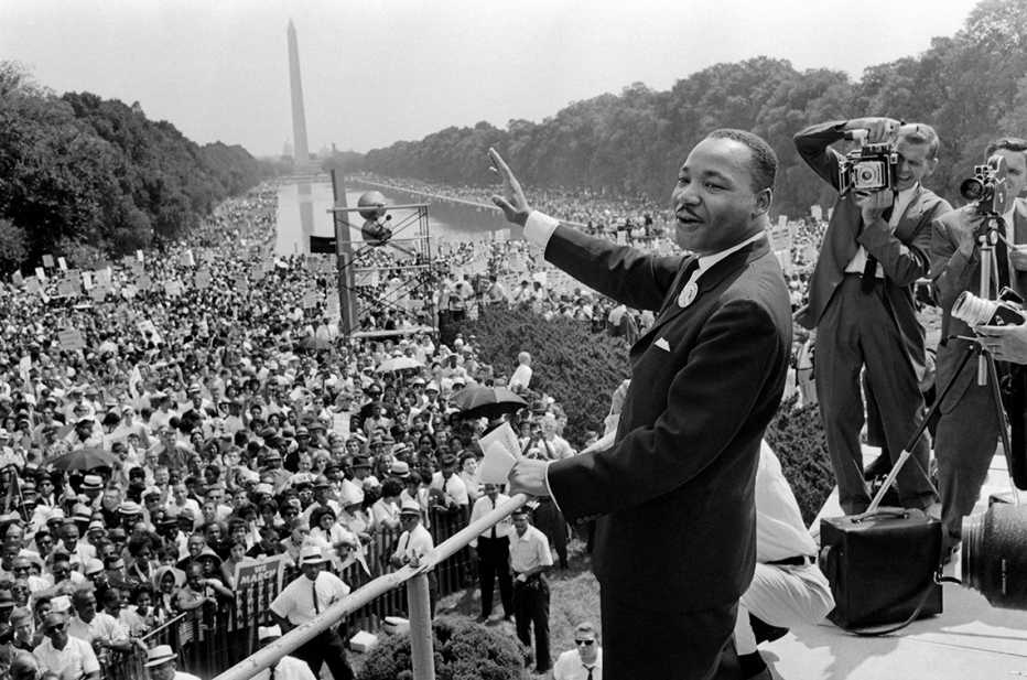 El líder estadounidense de derechos civiles Martin Luther King (centro) saluda a los manifestantes el 28 de agosto de 1963, en el Mall de Washington DC, durante la Marcha sobre Washington, donde King pronunció su famoso discurso “Tengo un sueño”, que movilizó a los partidarios de la abolición de la segregación y impulsó la Ley de Derechos Civiles de 1964.