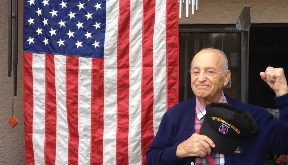 Robert Goyer, veterano de la Segund Guerra Mundial parado frente a una bandera de Estados Unidos