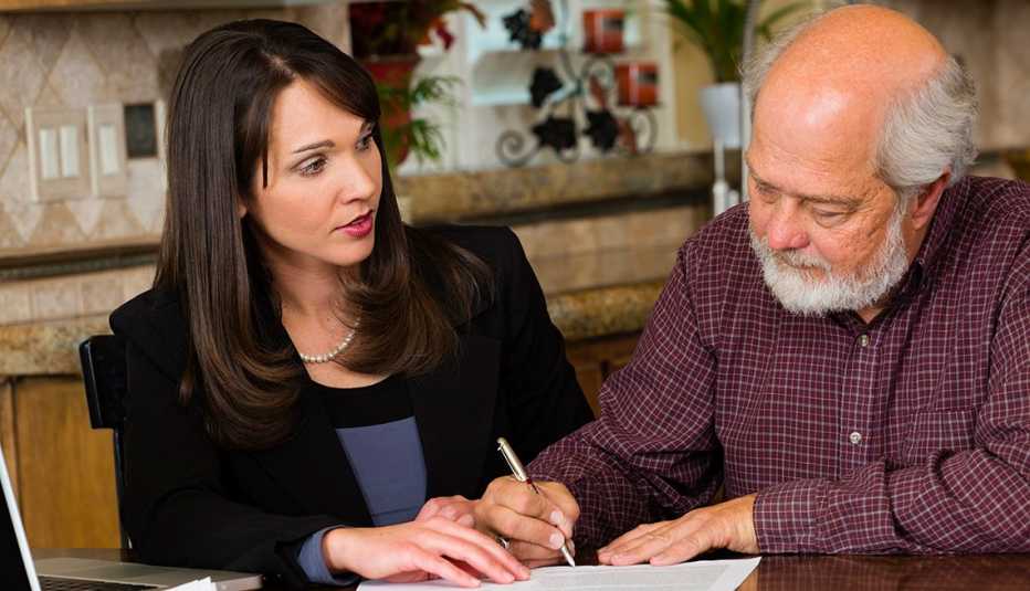 Hombre mayor firma un documento legal en compañía de una mujer joven