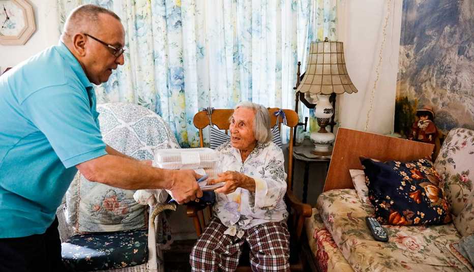 Hombre le entrega una caja con comida a una mujer anciana