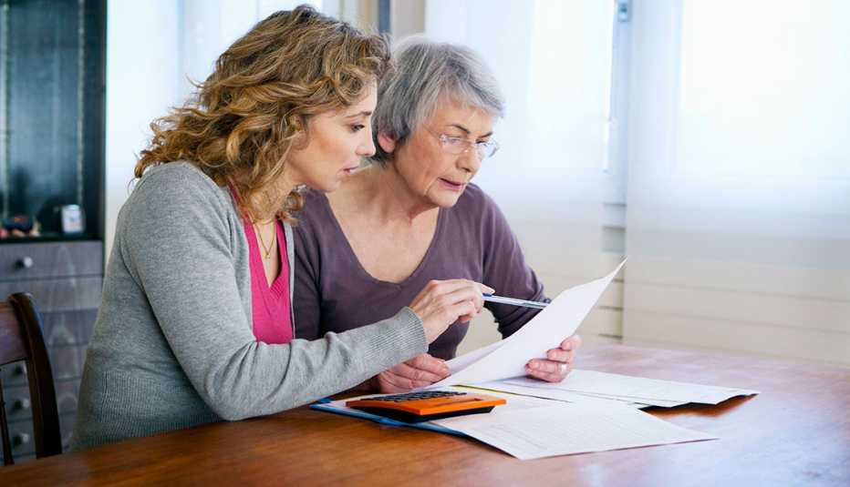 Mujer mayor con su cuidadora calculando facturas.