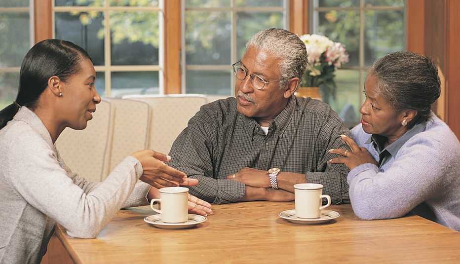 Mujer adulta sentada con sus padres en la mesa de la cocina discutiendo sus planes en caso de una emergencia