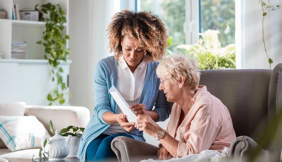 Un cuidador sostiene una hoja de papel mientras ayuda a una mujer a revisar sus opciones para pagar el cuidado a largo plazo.