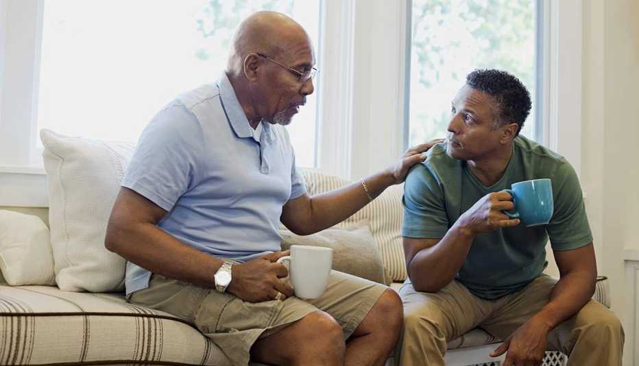 Padre e hijo conversan sentados en un sofá mientras toman un café