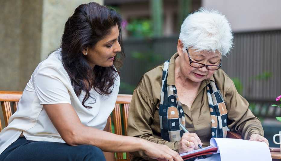 Una mujer ayuda a una persona mayor con documentos.