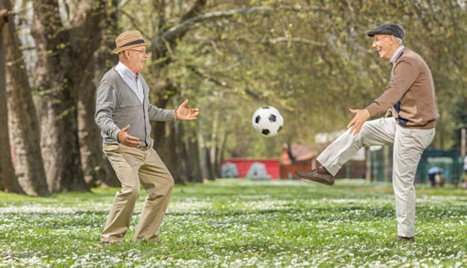 Dos hombres mayores juegan con un balón de fútbol.