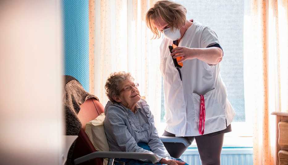 Un asistente de un hogar de ancianos sostiene un teléfono para ayudar a un residente de un hogar de ancianos con una visita virtual