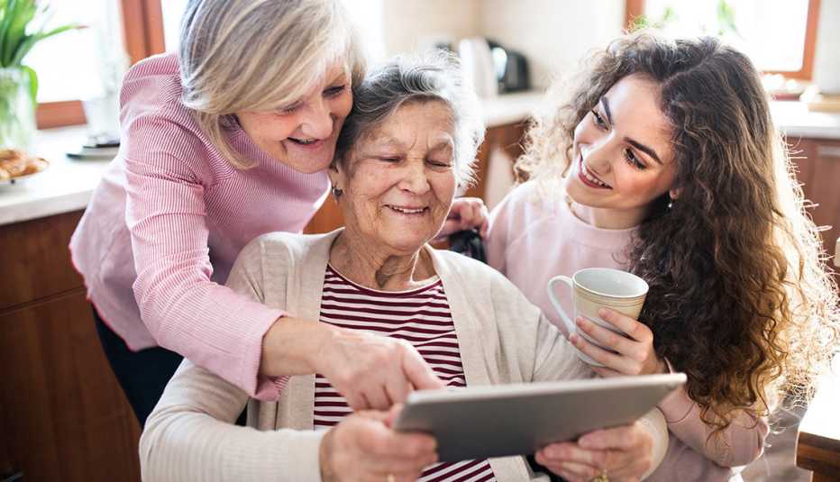 Tres generaciones de mujeres, abuela, hija y nieta usando una tableta