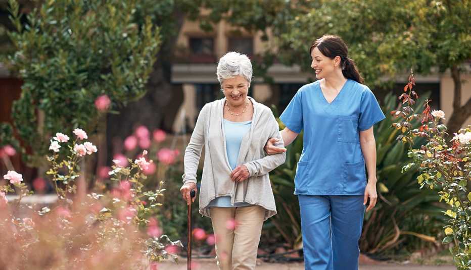 Una mujer y una enfermera caminando en un jardín.