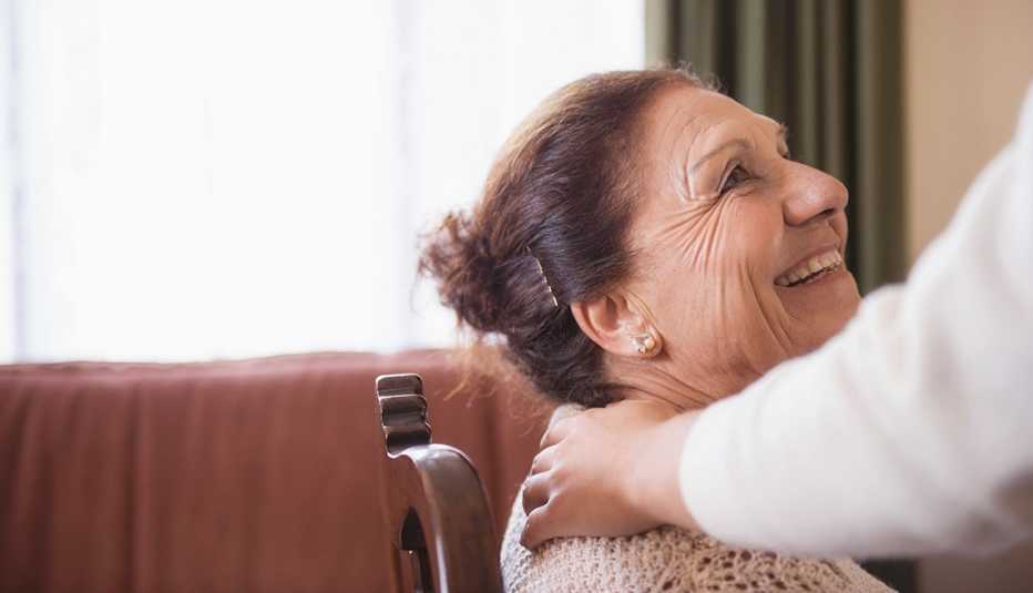 Mujer sentada sonríe a alguien que le pone una mano sobre su hombro - Estrategias para conductas difíciles de manejar