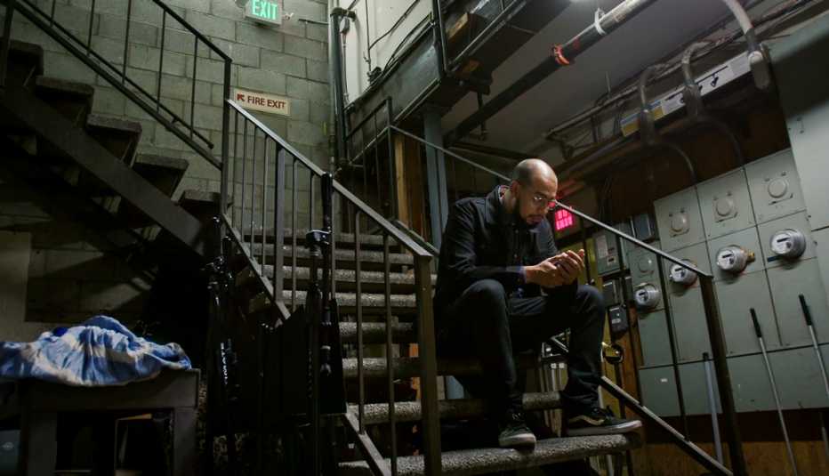 El comediante Jesús Trejo mira su celular sentado en una escalera