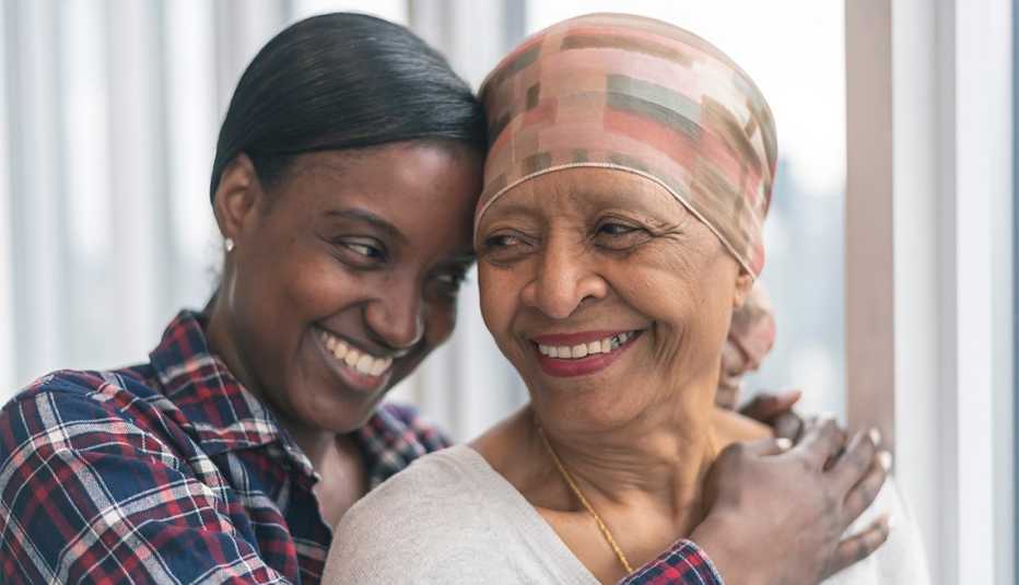 Una mujer joven abraza a una mujer mayor con cáncer.