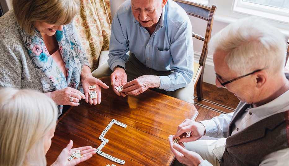 Dos hombres y dos mujeres mayores juegan dominó