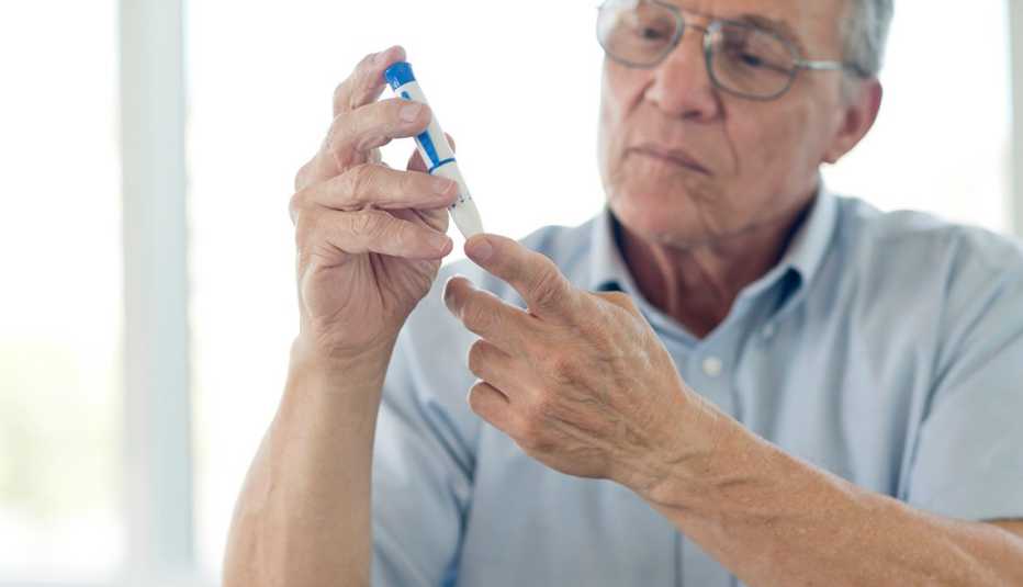 Hombre mayor haciendo una prueba de azúcar en un dedo.
