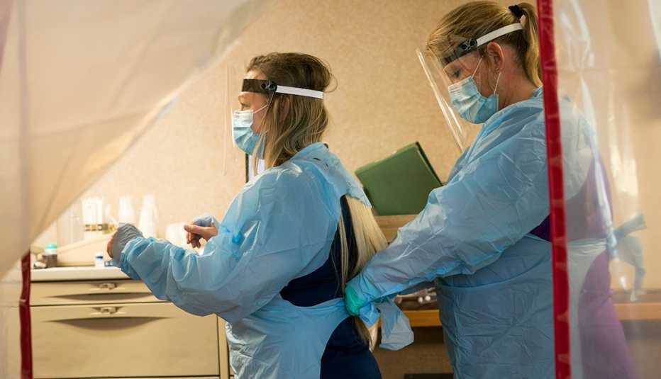Dos enfermeras se ponen el equipo de protección antes de entrar a una habitación