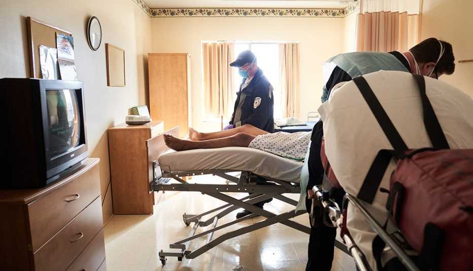 Dos empleados de emergencias se llevan a un paciente de coronavirus de un hogar de ancianos