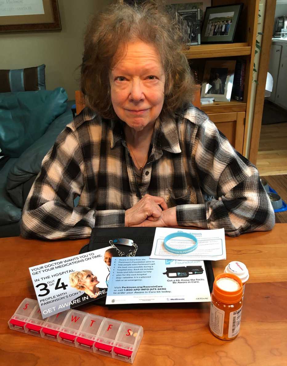  Andrée Jannette sentada en una mesa con un kit de atención consciente que incluye medicamentos y un frasco de pastillas