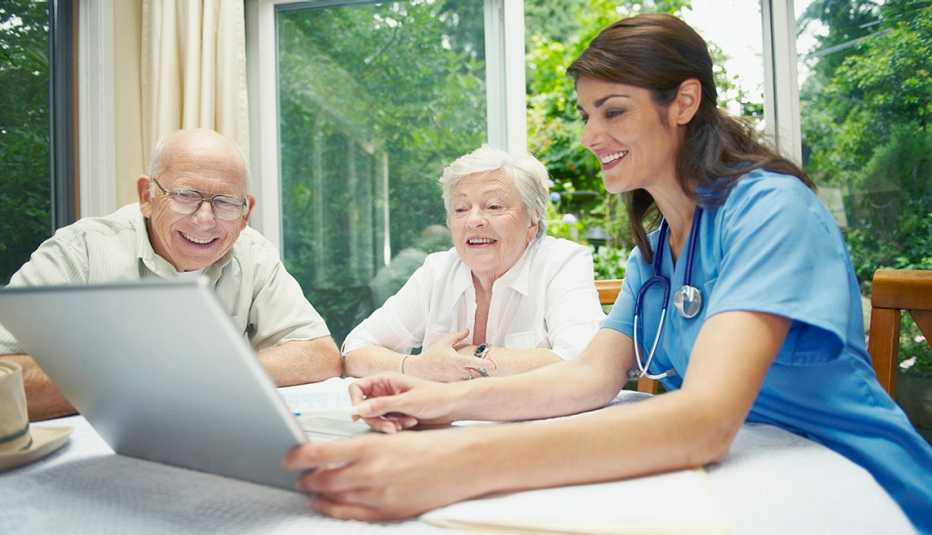Una enfermera le muestra un documento en una computadora a una pareja de ancianos