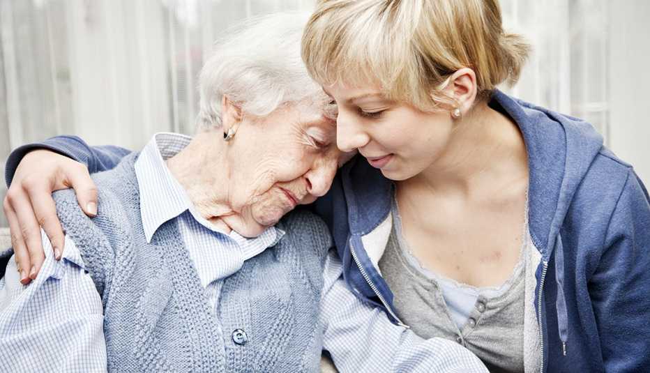 Una mujer mayor reclina cariñosamente su cabeza sobre el hombro de una mujer más joven.