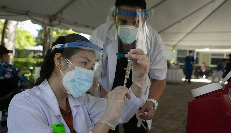 Trabajadores de la salud se preparan para poner una vacuna a un paciente.