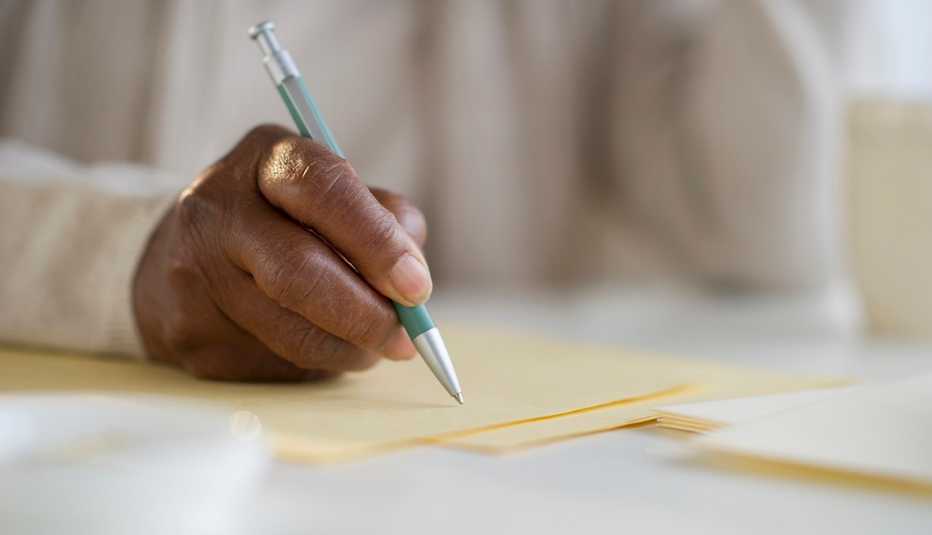 Primer plano de una mano de una mujer escribiendo una carta.