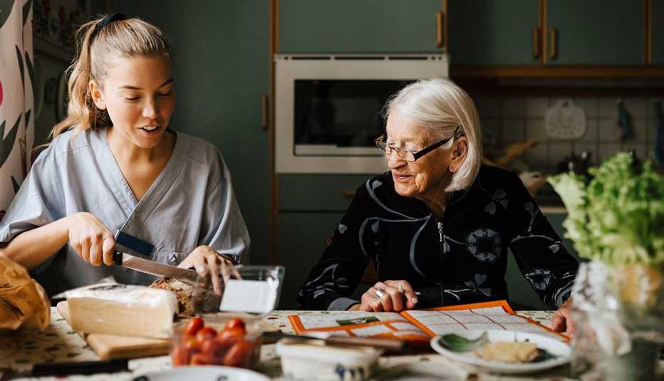 Una cuidadora ayuda a una mujer mayor a preparar un emparedado