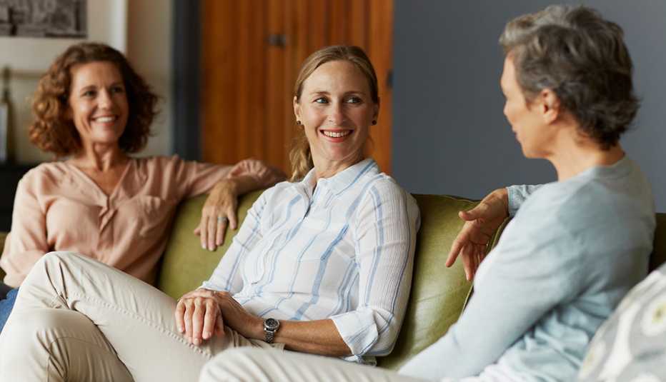 Tres mujeres sentadas en un sofá hablando durante un grupo de apoyo para cuidadores.