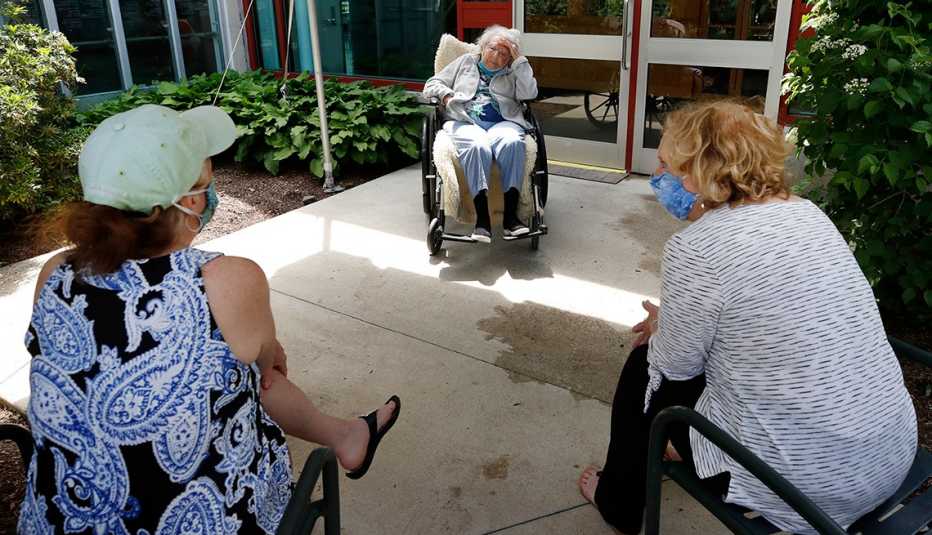 Dos mujeres con mascarillas visitan a su madre fuera de un hogar de ancianos