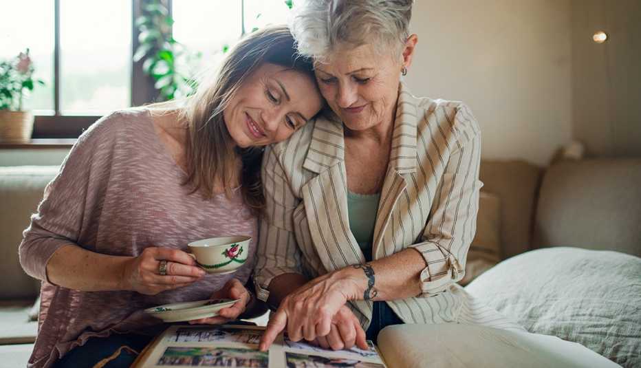 Una madre y su hija adulta miran un álbum de fotos familiares