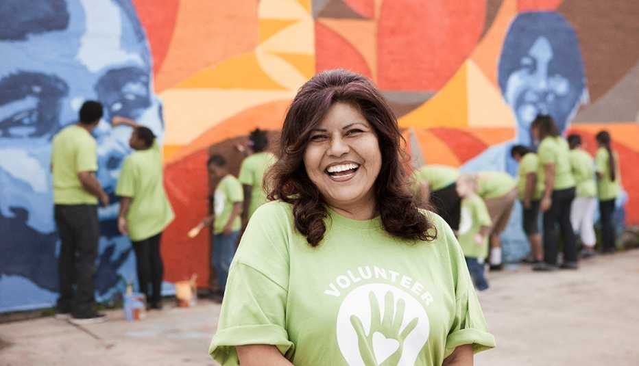Mujer hispana sonríe con una camiseta que dice voluntaria.