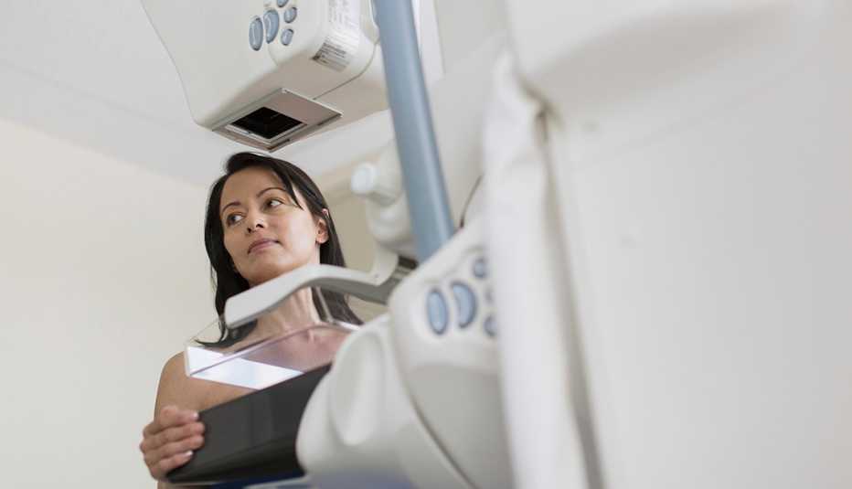Mujer mirando hacia el costado y enfrente de una máquina de mamografía