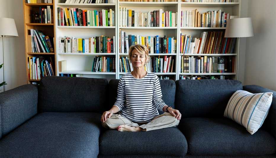 Una mujer medita en la sala de su hogar