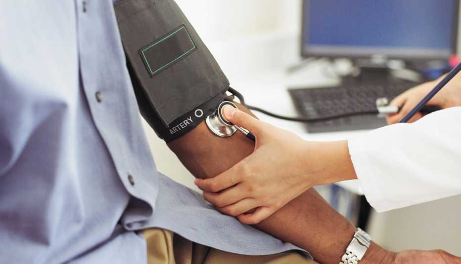 Un médico le toma la presión arterial a un paciente