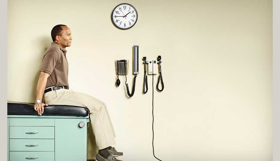 Hombre afro-americano sentado en una mesa en una consulta médica.